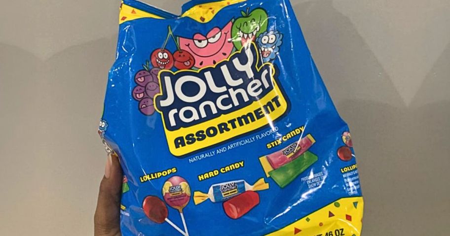 Hand holding up a big bag of assorted Jolly Rancher Candies