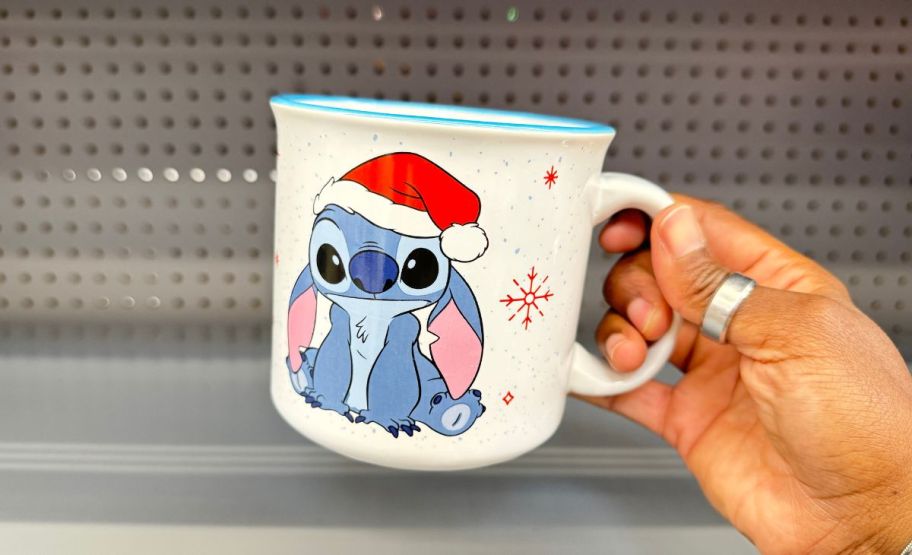 a womans hand holding a stitch holiday mug