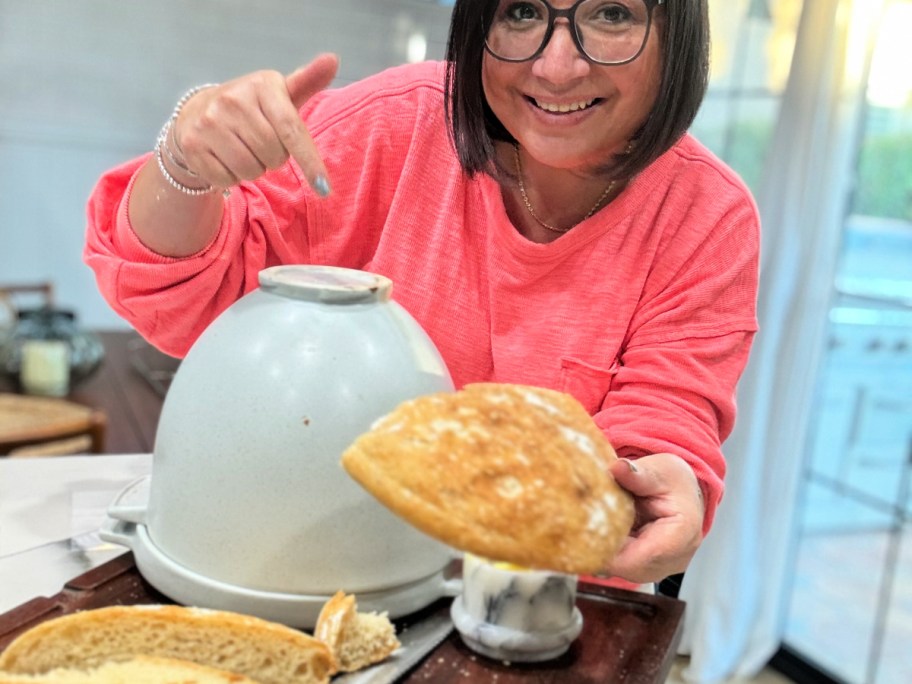 woman holding loaf of bread and pointing to kitchenaid bread bowl