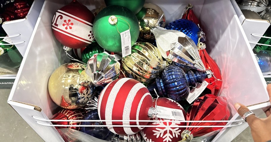 hand touching box of assorted christmas ornaments