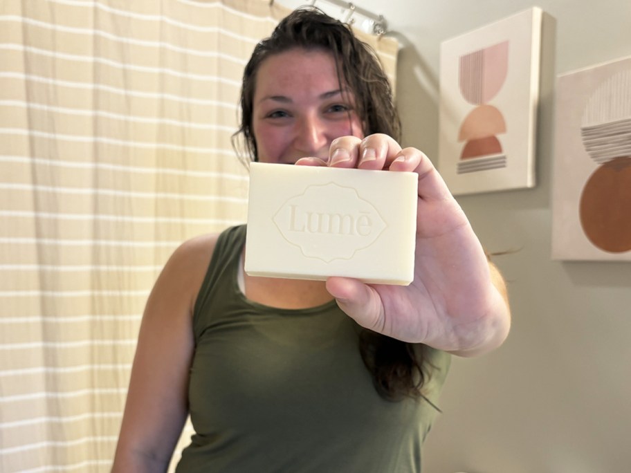 woman in bathroom holding up a bar of lume soap