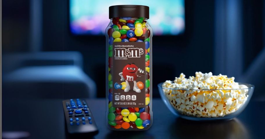 M&M's Milk Chocolate 25.5oz Candy Jar on table next to remote and popcorn bowl