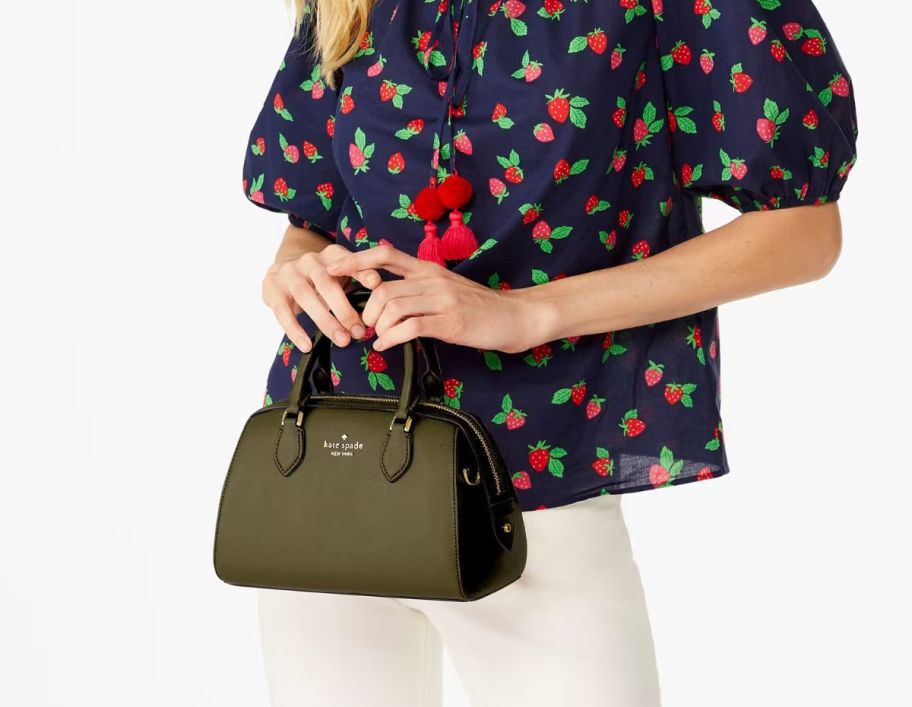 a woman holding a small satchel bag