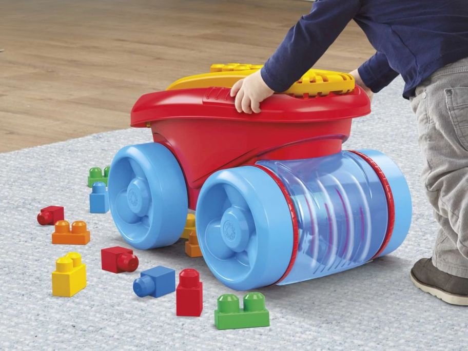 kid pushing Mega Bloks Blue Block Scooping Wagon Building Toy across floor