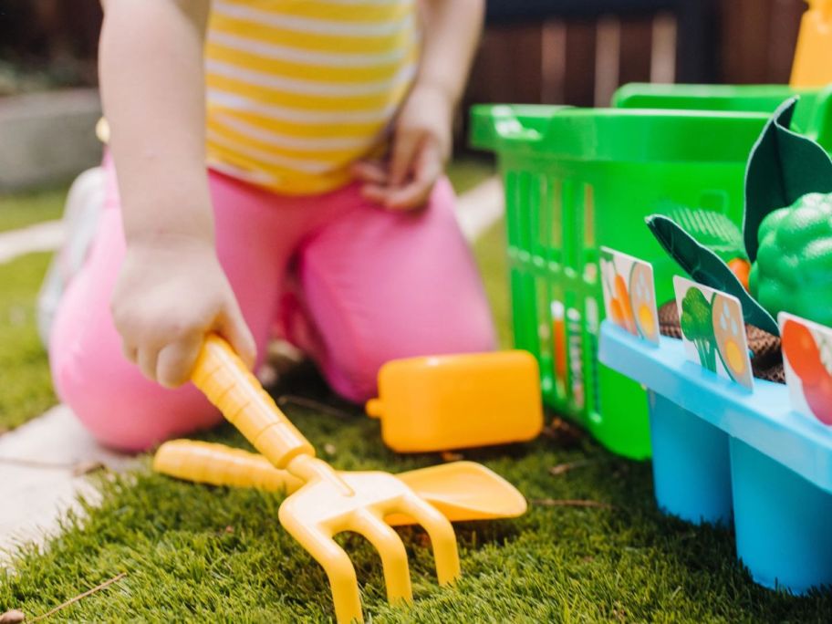 girl using Melissa & Doug Let's Explore Vegetable Garden Play Set w/ Plastic Rolling Cart outside