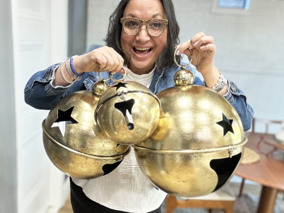 woman holding up three large hold jingle bell balls