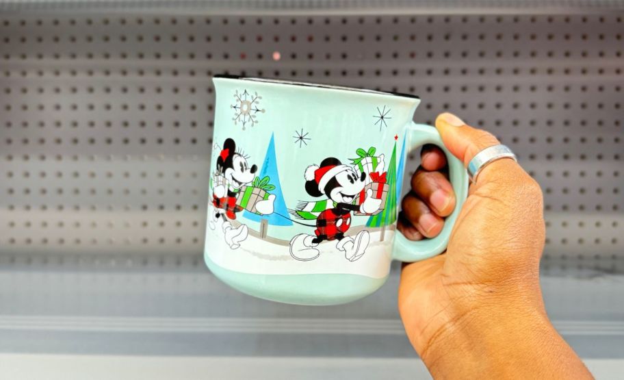 a womans hand holding mickey & minnie mouse holiday mug