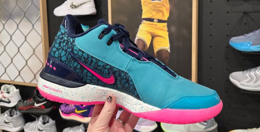 womans hand holding a teal nike mens basketball shoe