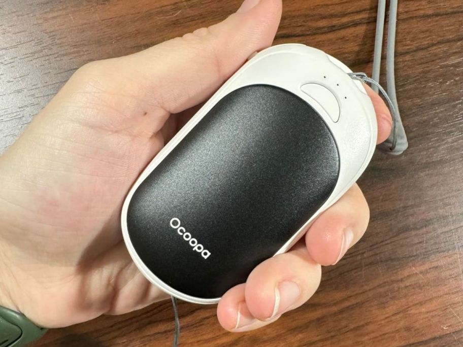 A person holding a OCOOPA Magnetic Rechargeable Hand Warmer