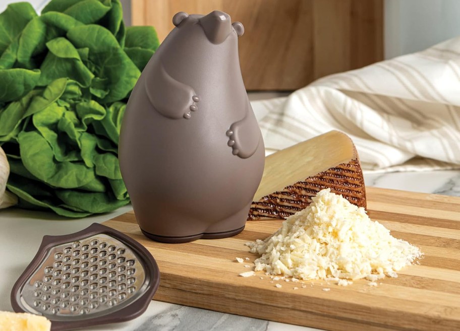 cheese grater with cheese on cutting board