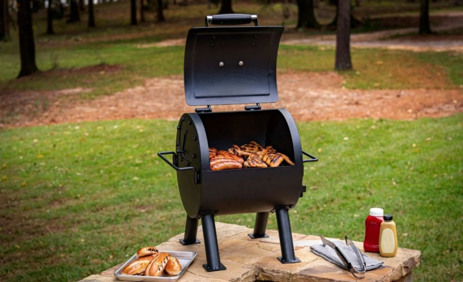  a hitch portable charcoal grill shown with food grilling on it