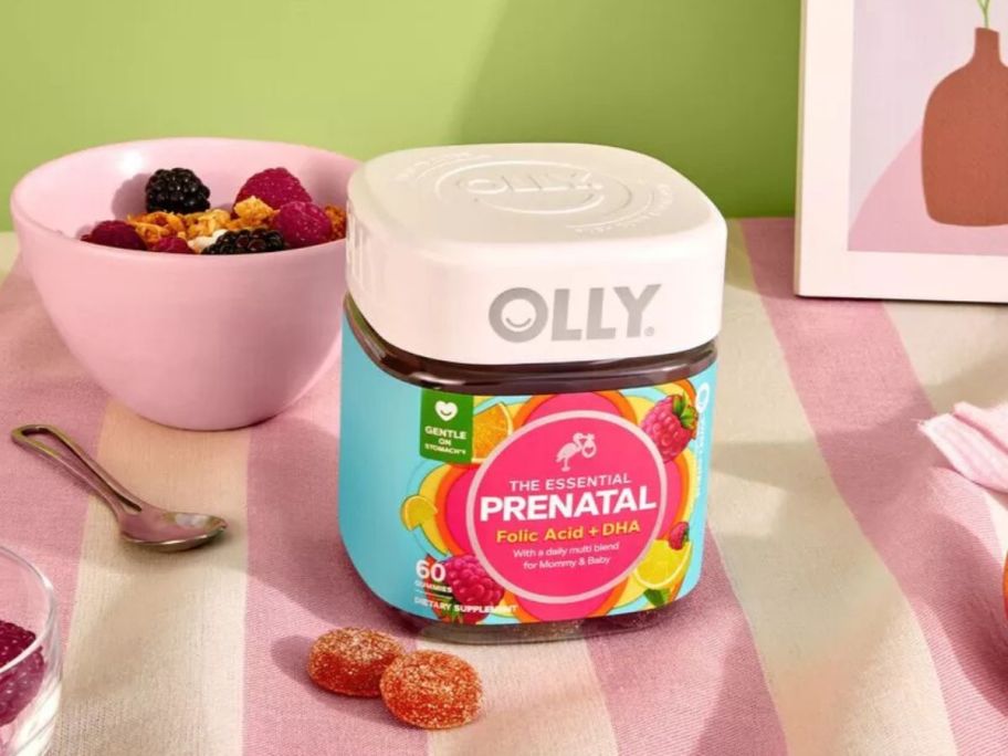 A jar of Olly prenatal Gummy Vitamins on a table nedxt to a bowl of cereal