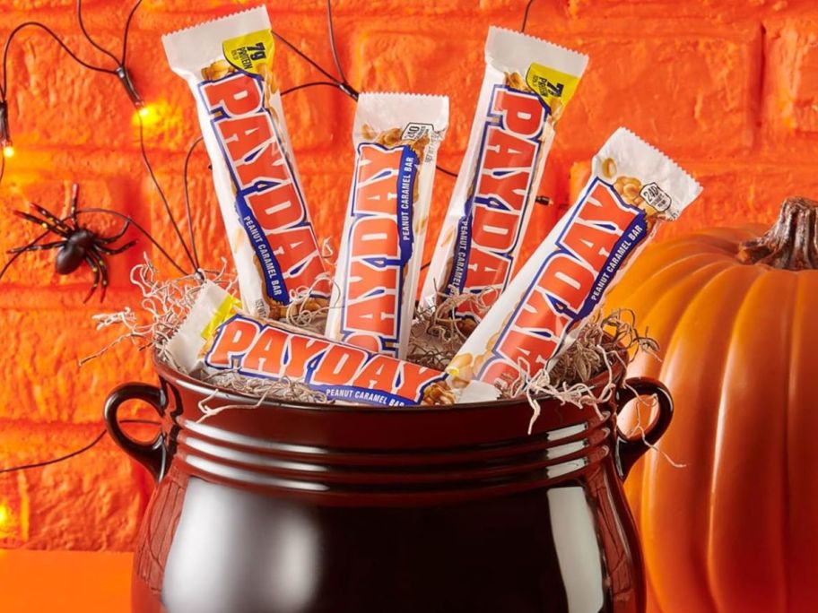 A black decorative cauldron filled with Payday candy bars