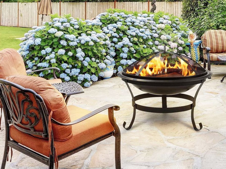 round fire pit in yard near patio chairs