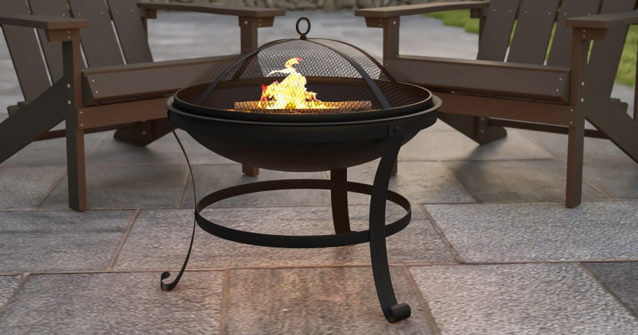 round black fire pit in front of two patio chairs