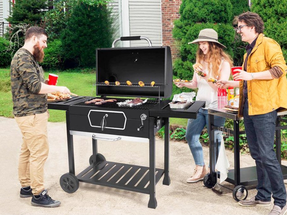 people standing around black grill