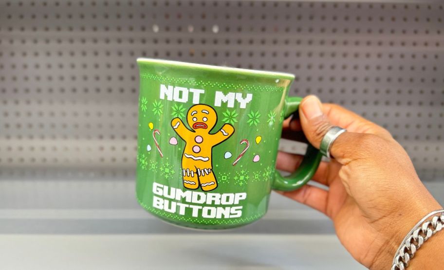 a womans hand holding a gingerbread man from shrek mug