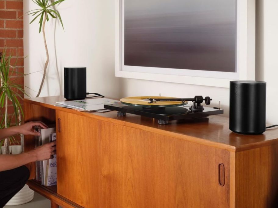 A media console with a record player and 2 Sonos Era Speakers on it