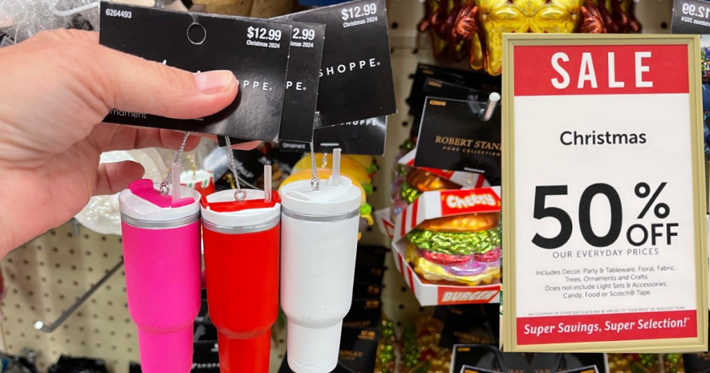 person holding mini stanley tumbler ornaments inside hobby lobby