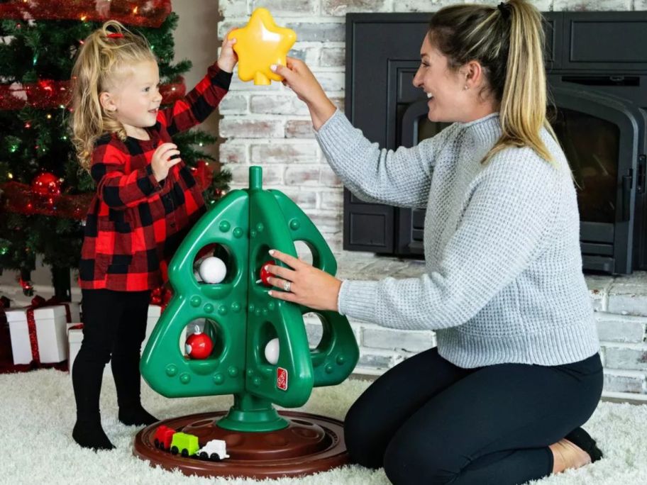 A mom helping a little girl with the star on the Step2 My First Christmas Tree 