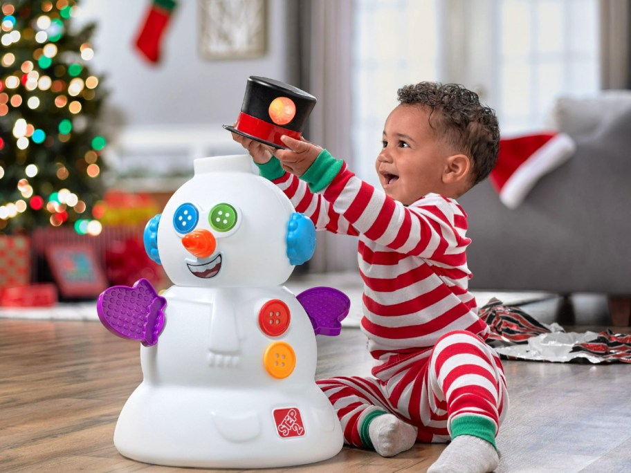 toddler in stiped Christmas pajamas playing with a Step2 My First Snowman