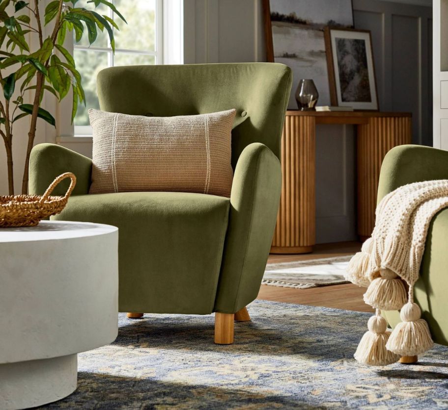 a green velvet accent chair with a beige throw pillow