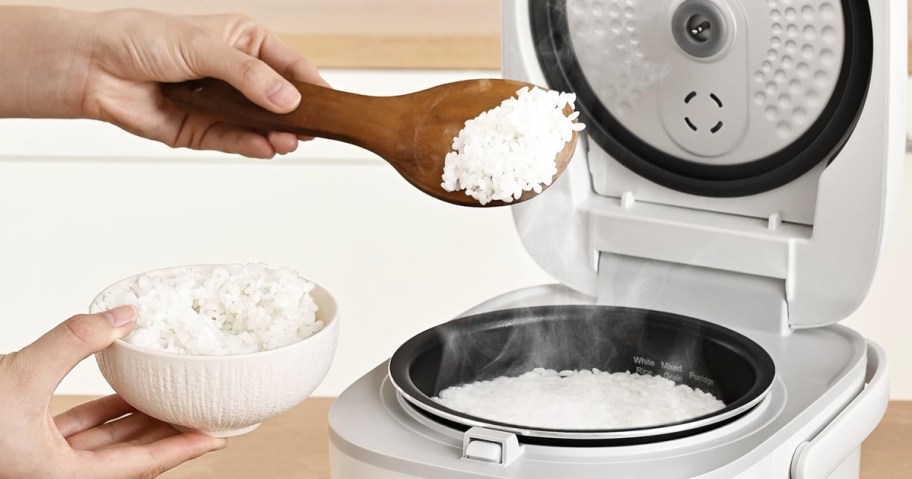 person taking rice out from a white rice cooker