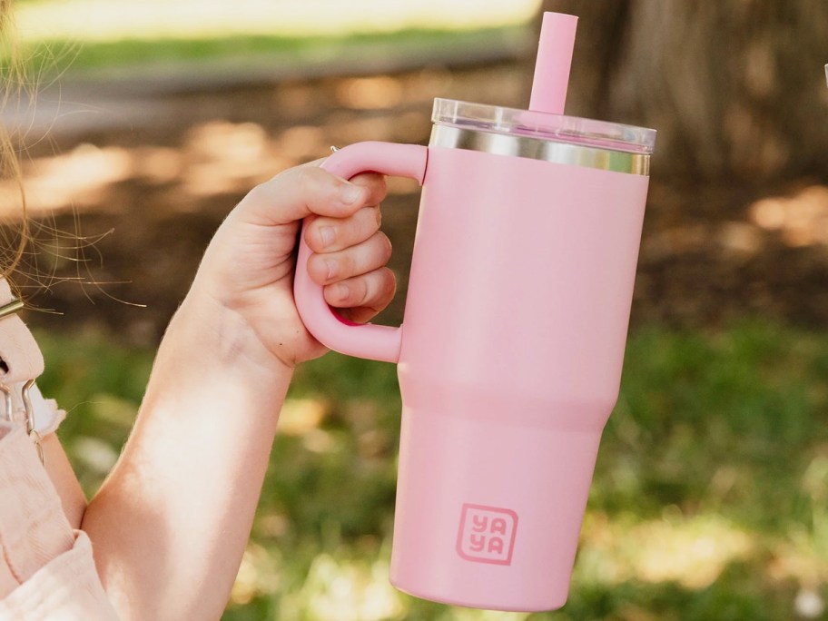 child holding up a light pink tumbler