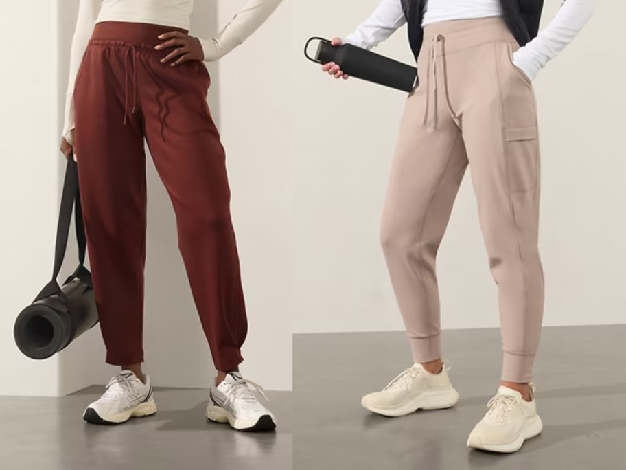 woman wearing dark red joggers and woman wearing light tan cargo joggers, both are holding yoga mats