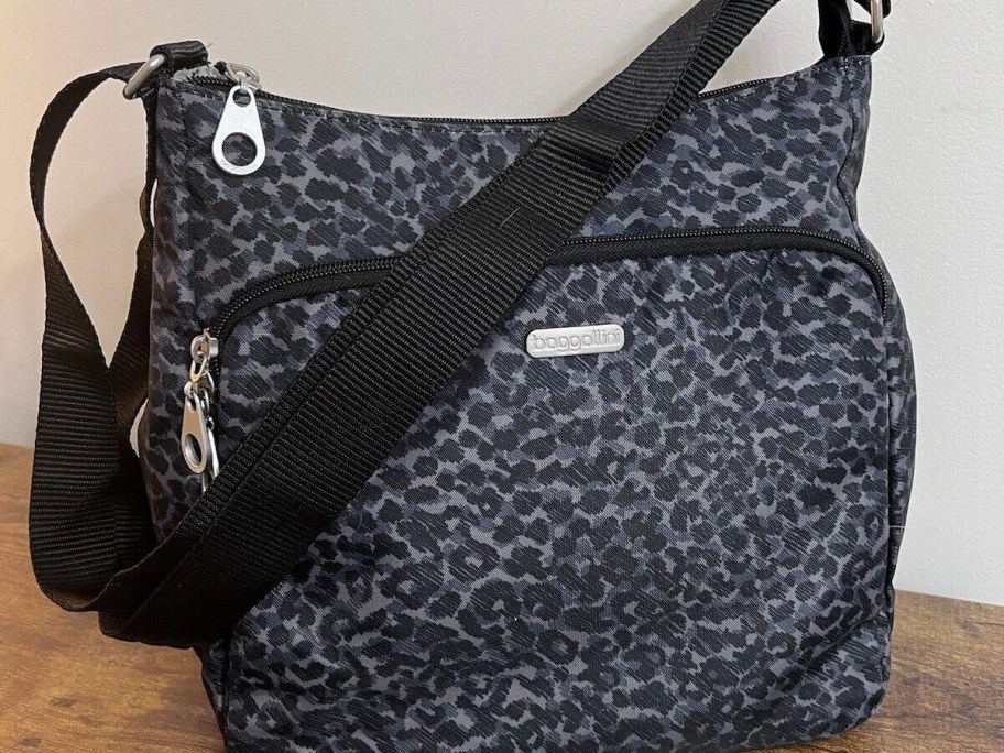 cheetah print black baggallini crossbody bag on table