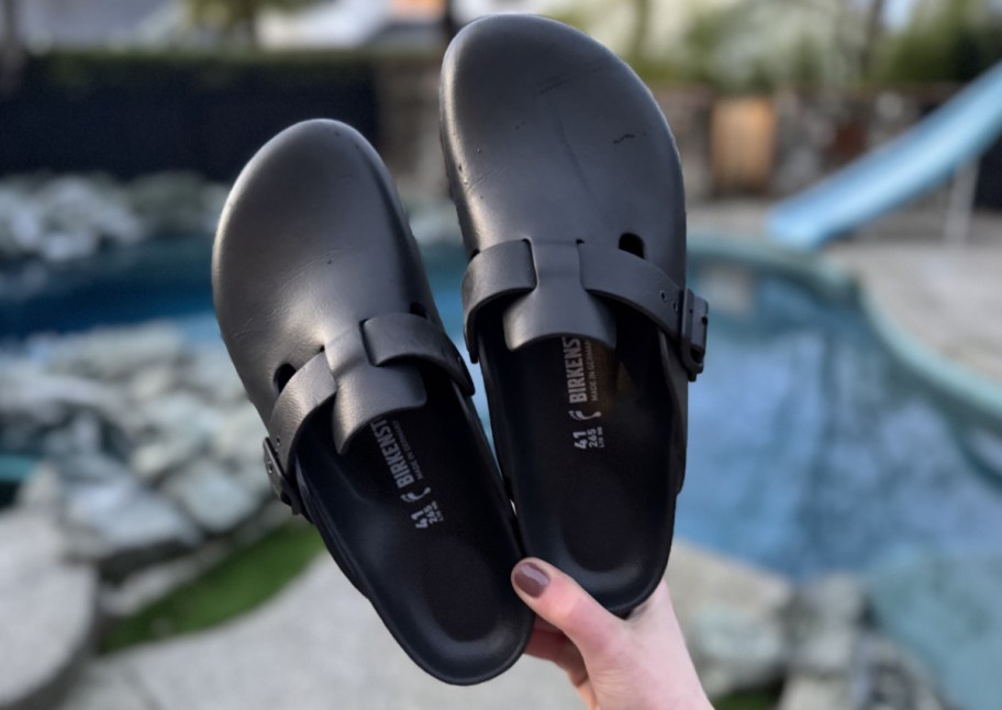 hand holding birkenstocks near pool