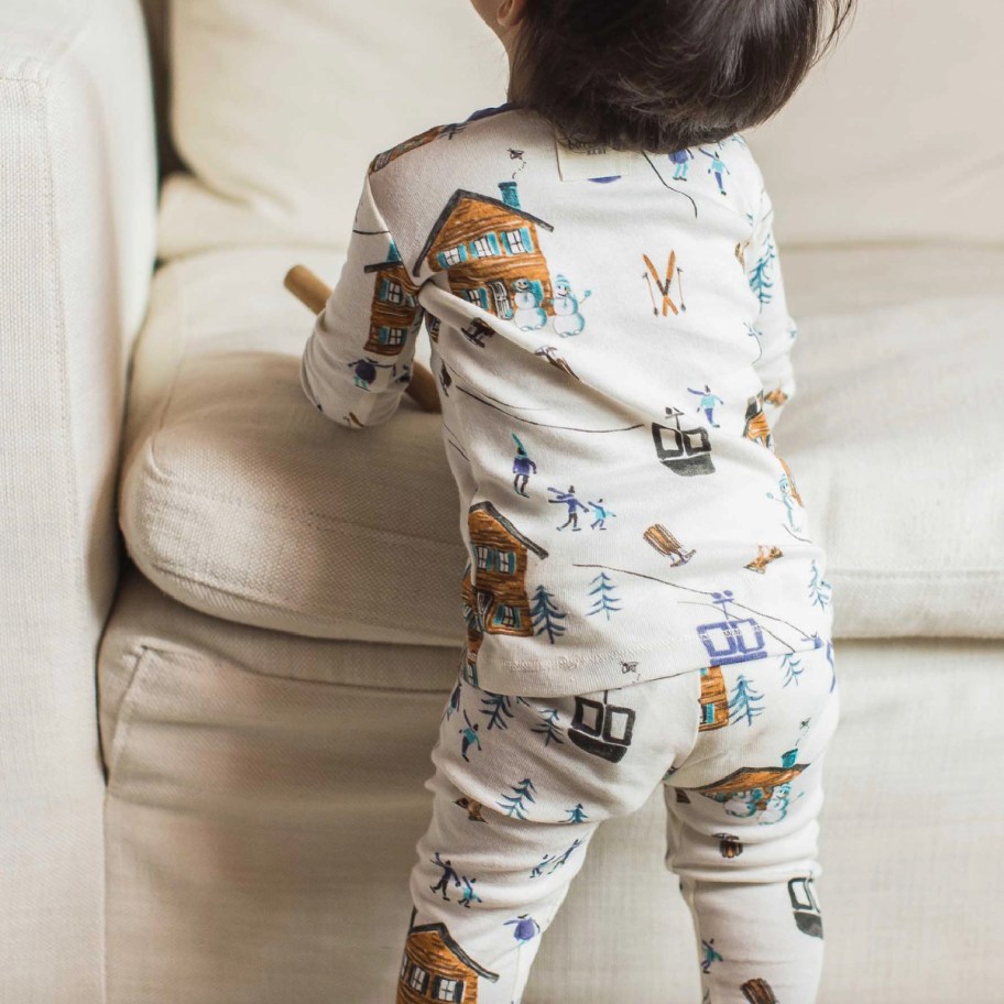 baby standing near couch in winter jammies