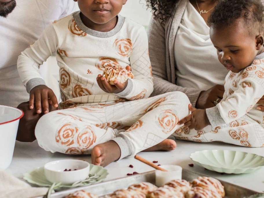 two kids making cinnamon rolls in cinnamon roll jammies