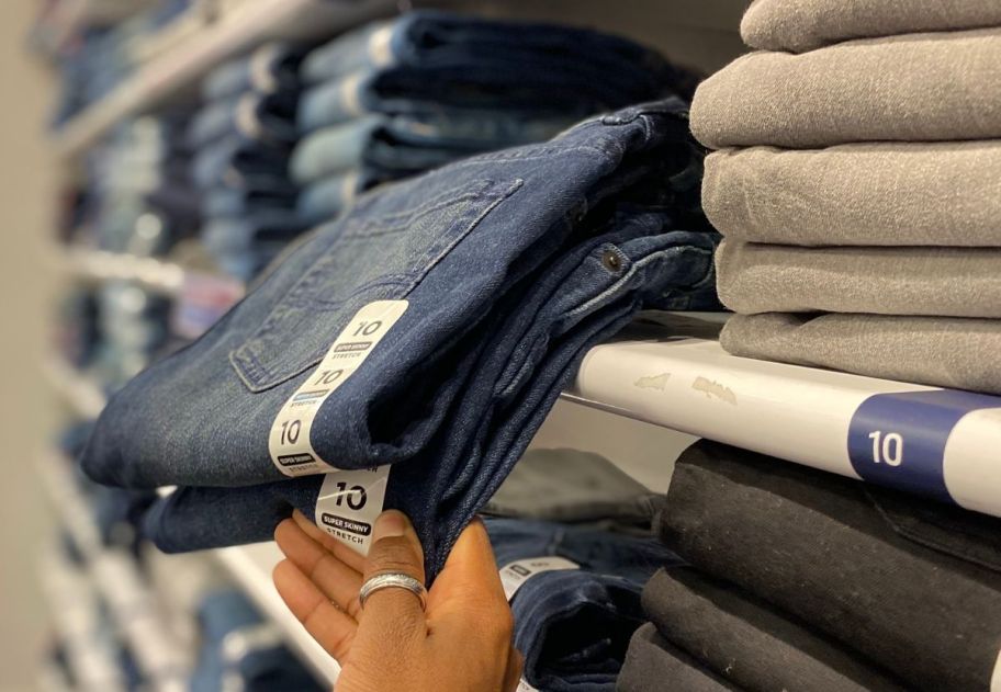 hand grabbing children's place jeans off a store shelf