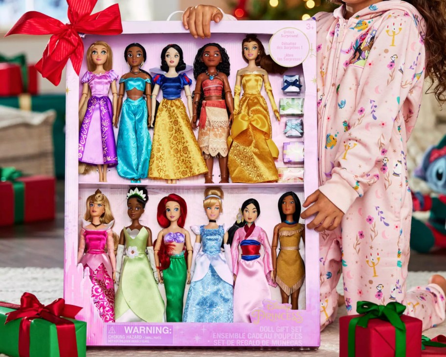 girl holding disney princess dolls in box