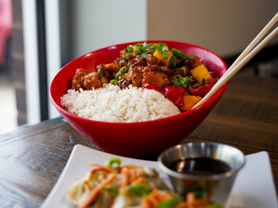 red bowl with rice, stir fry, and chopsticks