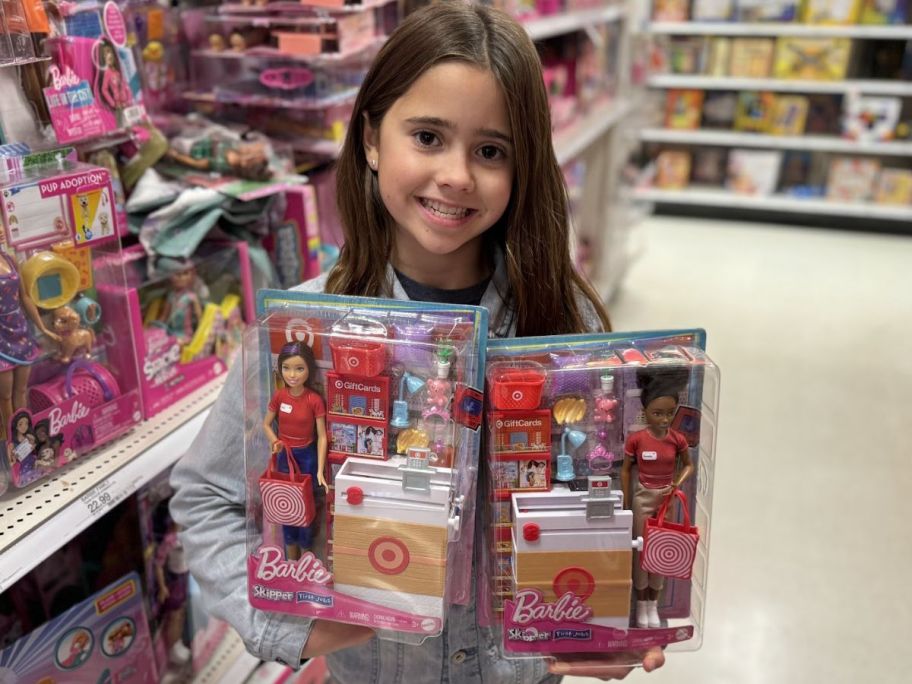 a little girl holding two target skipper dolls on a toy aisle