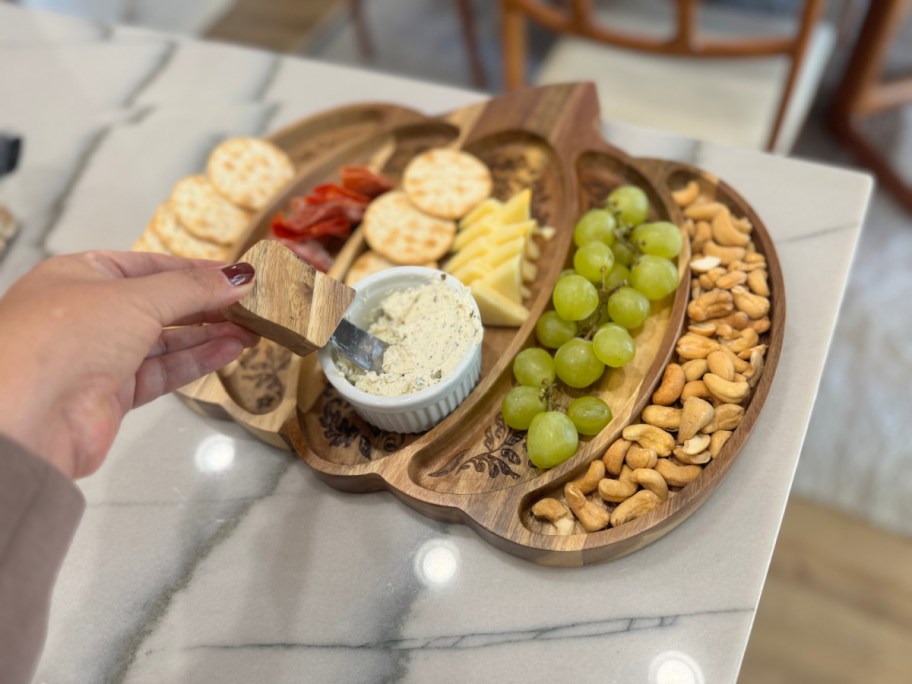 pumpkin shaped charcuterie board filled with fruit, nuts, crackers, meat and cheese