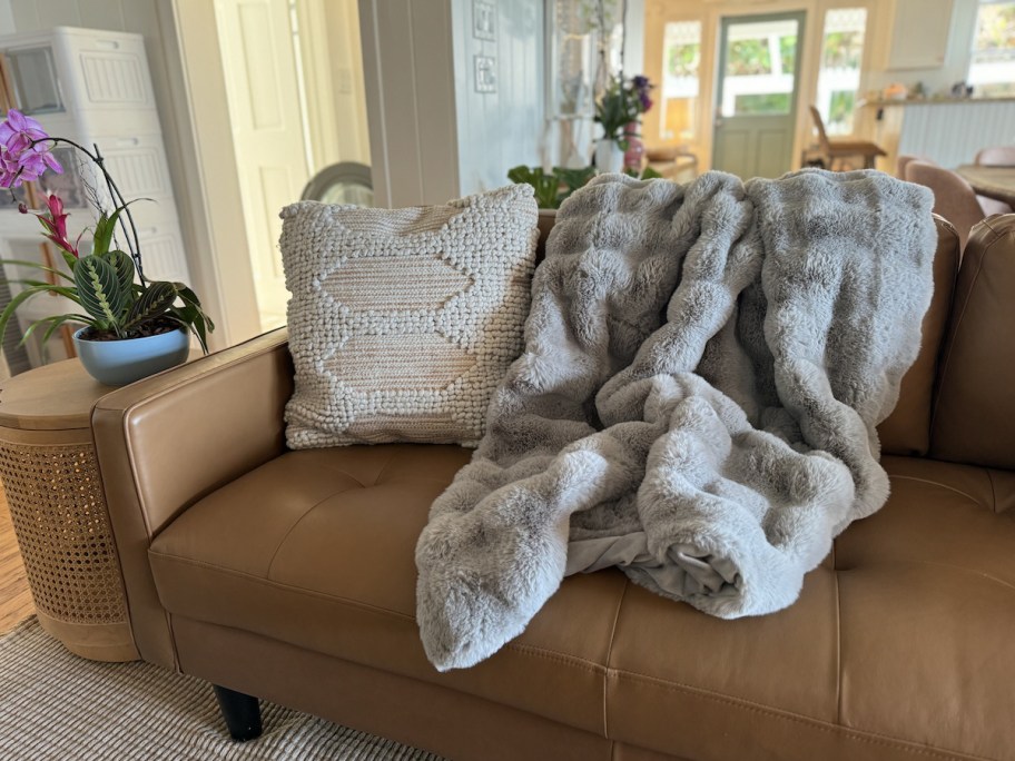 gray faux fur throw blanket on brown leather couch