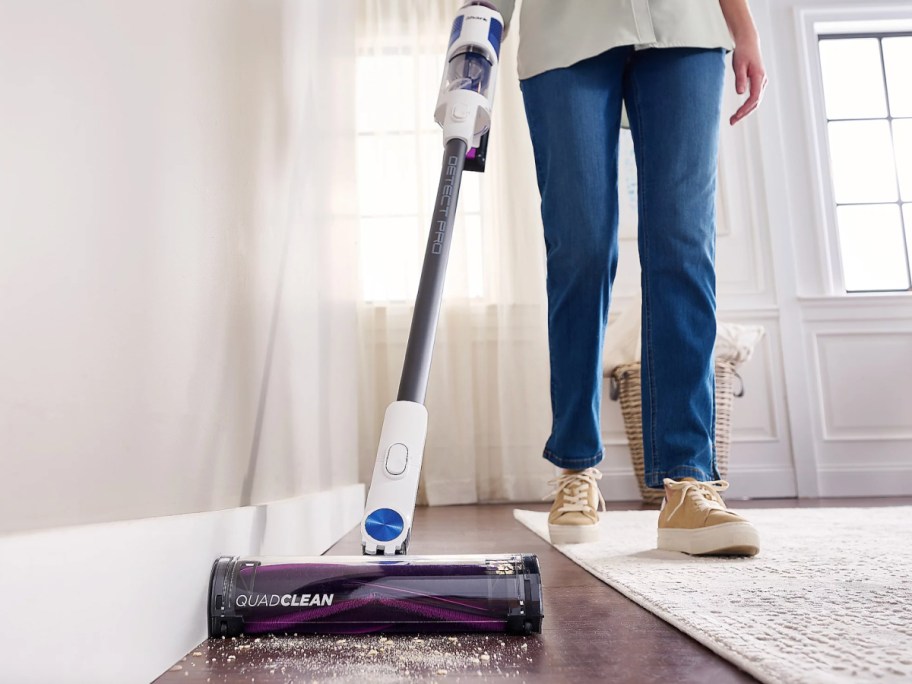 person vacuuming with stick vac