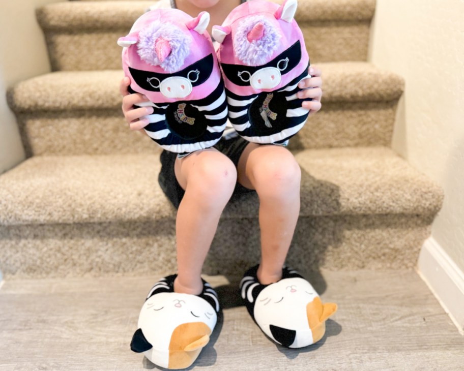 boy sitting on stairs wearing and holding slippers