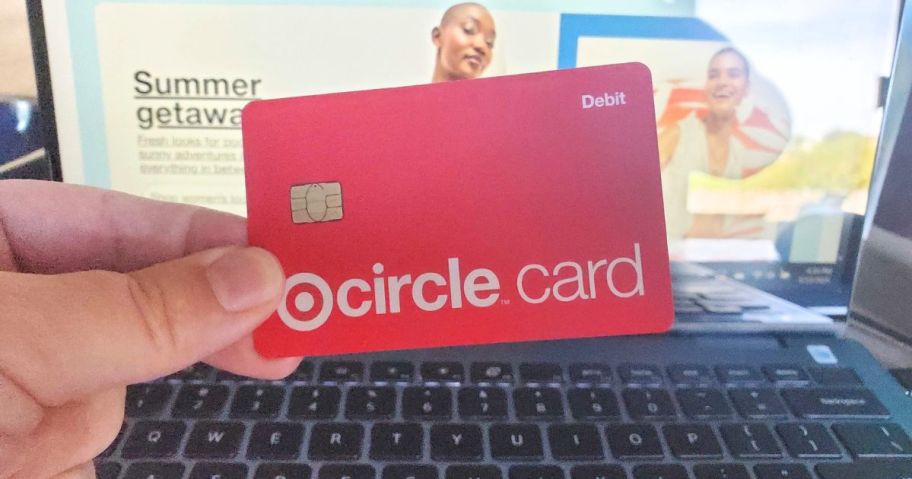 target circle card in hand in front of laptop