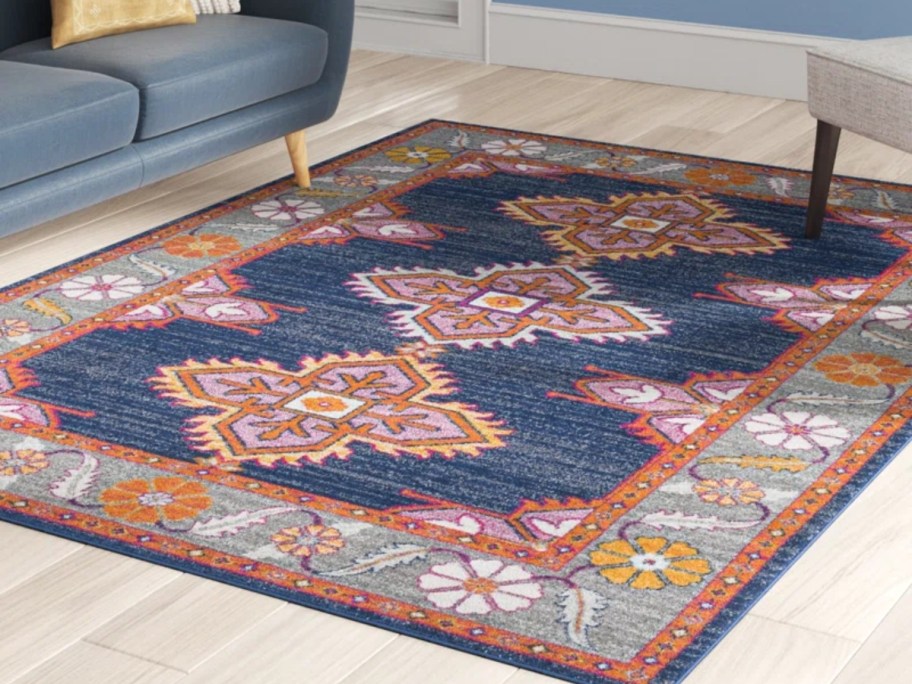 a blue, orange, red and white print area rug in a living room