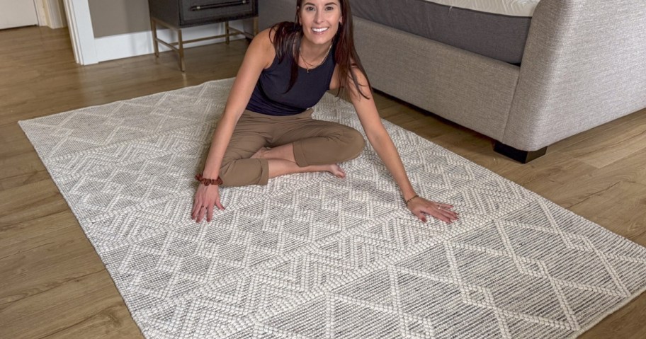 a woman sitting on a grey and cream wool area rug