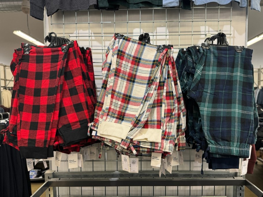 3 pairs of plaid flannel pajama joggers hanging on a wall display in store