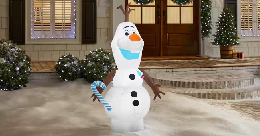 olaf holding candy cane inflatable in yard