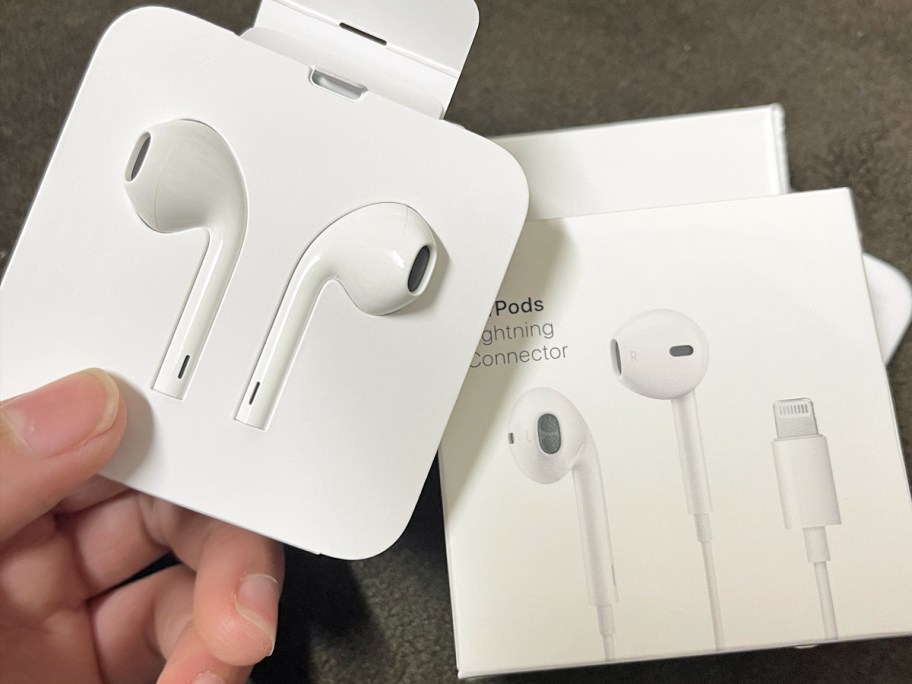 hand holding a white set of Apple EarPods Headphones