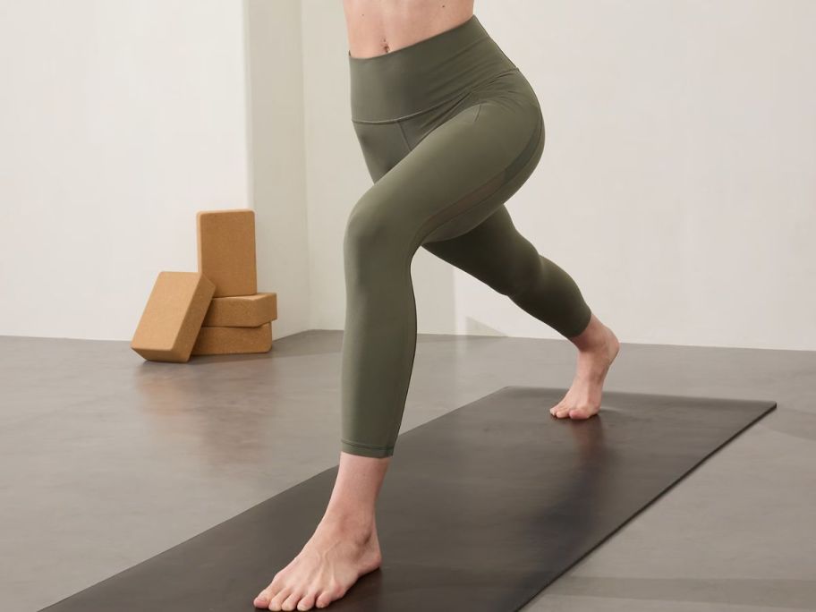 Woman wearing Athleta Salutation Stash High Rise Mesh 7/8 Legging while doing yoga