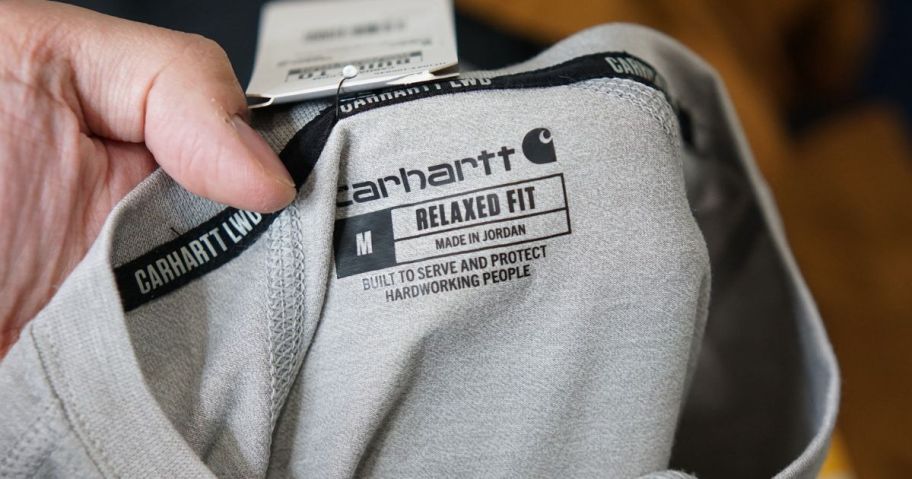 Hand Holding a Carhartt Shirt showing the tag