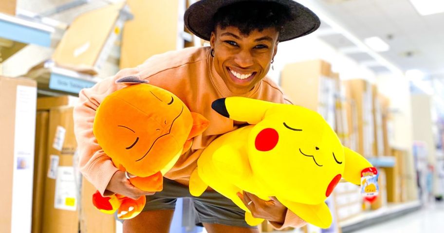 Woman holding two Cuddleez Target Pokemon Sleeping Plush Pillows in Charmander and Pikachu